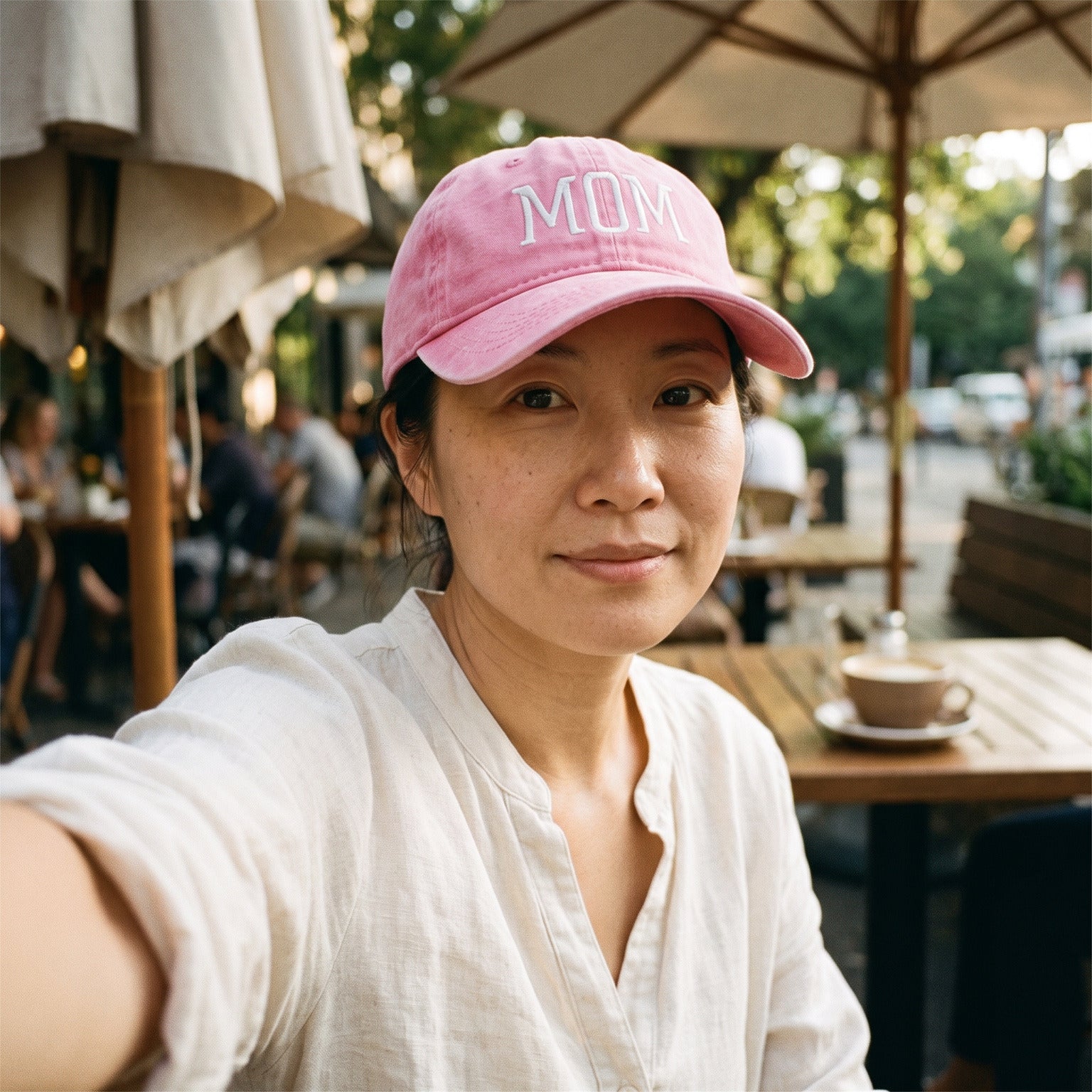 Mum taking a café selfie wearing her Pink MOM cap